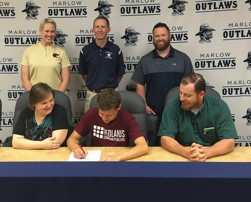 Andrew Brown signs a Letter of Intent while his family and coaches look on. Front row: Stacy Brown, Andrew Brown, James Brown. Back row: Redlands Cross Country Head Coach Natalie Cox, Marlow Cross Country Assistant Coach Matt Ivory, Marlow Cross Country Head Coach Mikey Eaves. Photo Submitted