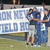 HONORED: Retired Marlow football coach Ron Newby receives a hug from his grandson, Brock Harris, during halftime of the Marlow and John Marshall football Friday night. The school district announced it was naming the football fieldhouse in Newby’s honor.