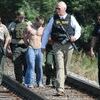 CAUGHT: Stephens County Sheriff Wayne McKinney leads a group of deputies and armed burglary suspect Andrew Dewayne Williams down railroad tracks following Williams’ capture. A two-hour manhunt took place for Williams near the Ballpark Apartments in Marlow after he fled on foot to avoid an arrest warrant.