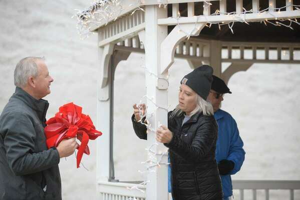 Last minute touches include checking the lights and adding holiday red bows to the Marlow gazebo on Main Street. Photo by Toni Hopper