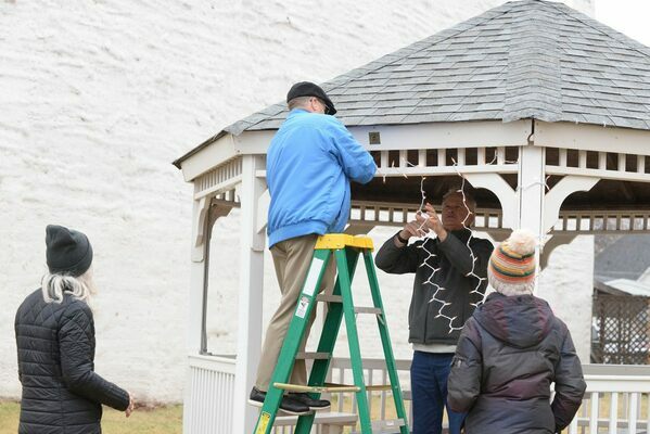 Jason McPherson takes his turn on the ladder Friday, Dec. 2, 2022, to help string lights on the gazebo on Marlow's Main Street while he gets help from Lynn Bailey, and encouragement from Kim Kizarr, right, and Destiny Ahlfenger. The gazebo is located in the 300 block, across from The Marlow Review. Photo by Toni Hopper/The Marlow Review