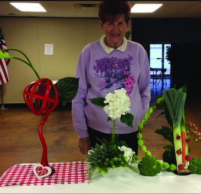 PATIO MEETS: At a recent Patio Garden Club meeting, Mrs. Shirley Johnston, shown above, created three floral designs that can be useful in a dining room or kitchen display.