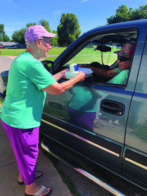 Nellie Carr, a volunteer with Marlow Senior Nutrition, delivers lunch to one of her “regulars” at the Redbud Community Center. Carr has worked every weekday at the Center since March 17,  serving drive-up meals to senior citizens in the area.
