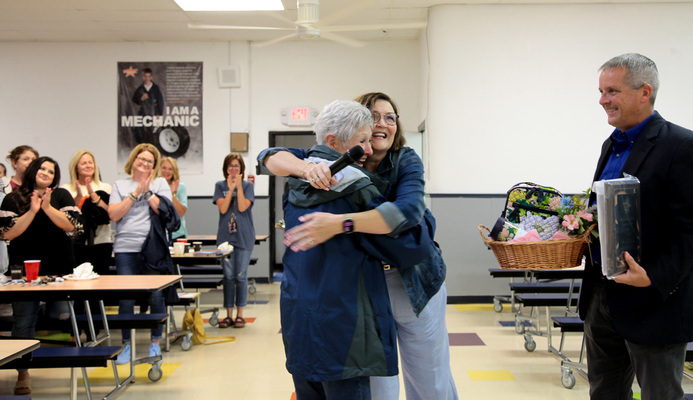 Pat McCauley and Brenda Parker-Tillian share a hug, as Superintendent Corey Holland and a cafeteria filled with teachers and other district staff members applaud. McCauley was named Support Person of the Year for the 2022-23 school year. She has been with the district for 30 years. She received a gift basket, a check from the district and other items, valued at over $1,300. Photo by Toni Hopper/The Marlow Review