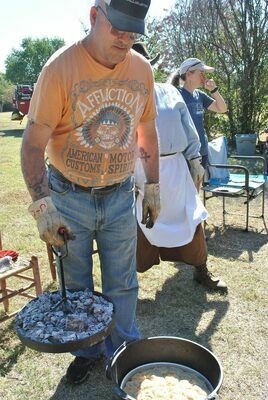 Brandon Dodson can usually be seen working alongside the Millers at the various chuckwagon cook-offs and events. He does the heavy lifting of the cast-iron pans and skillets that Carlann Miller keeps filled with either sourdough biscuits or deep dish peach cobbler. There's usually always a line waiting for the biscuits. Photo by Toni Hopper/The Marlow Review